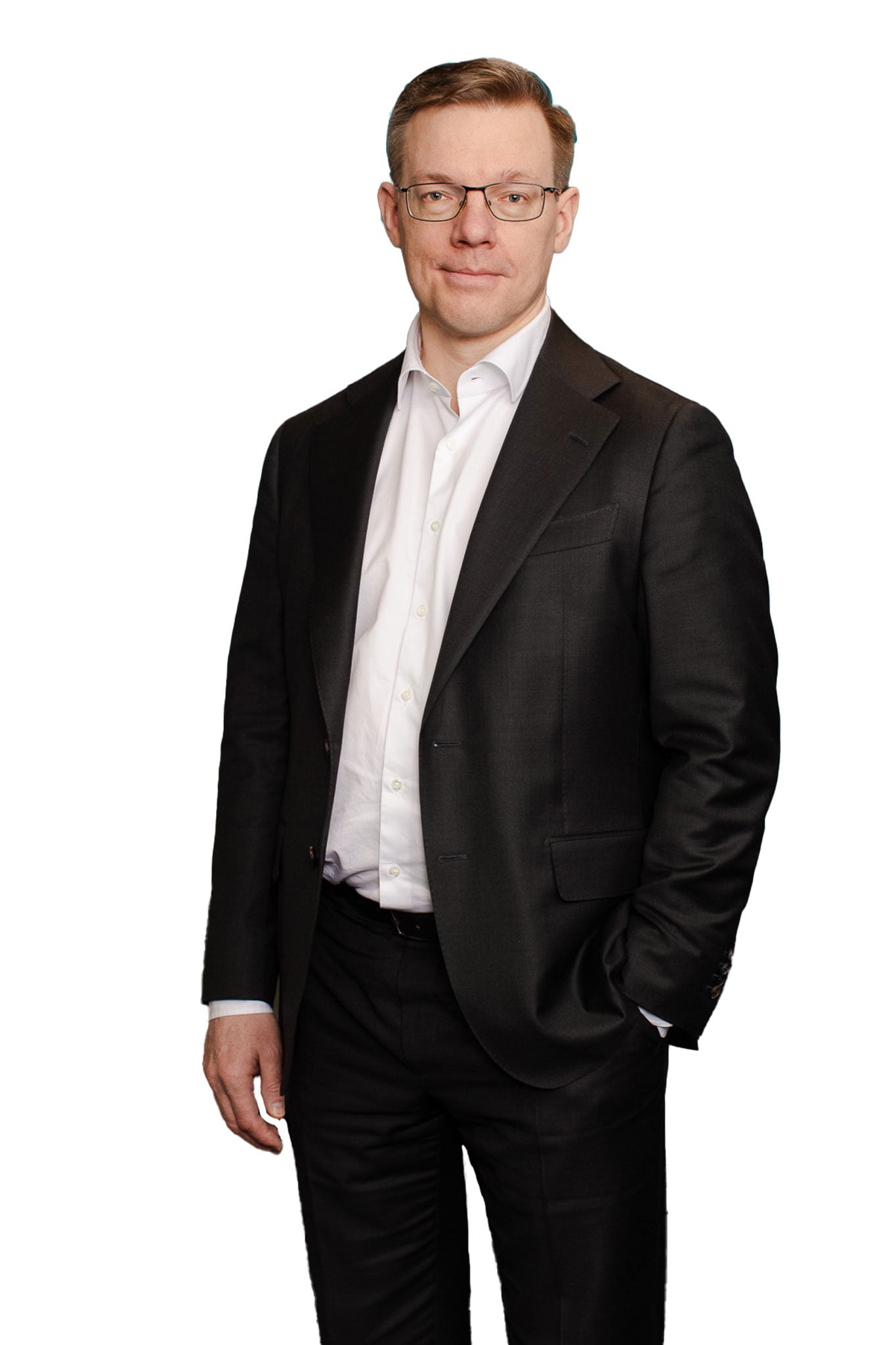 Karo Nukarisella on tumma puku päällä, yksi käsi taskussa ja katsoo kameraan hymyillen.
